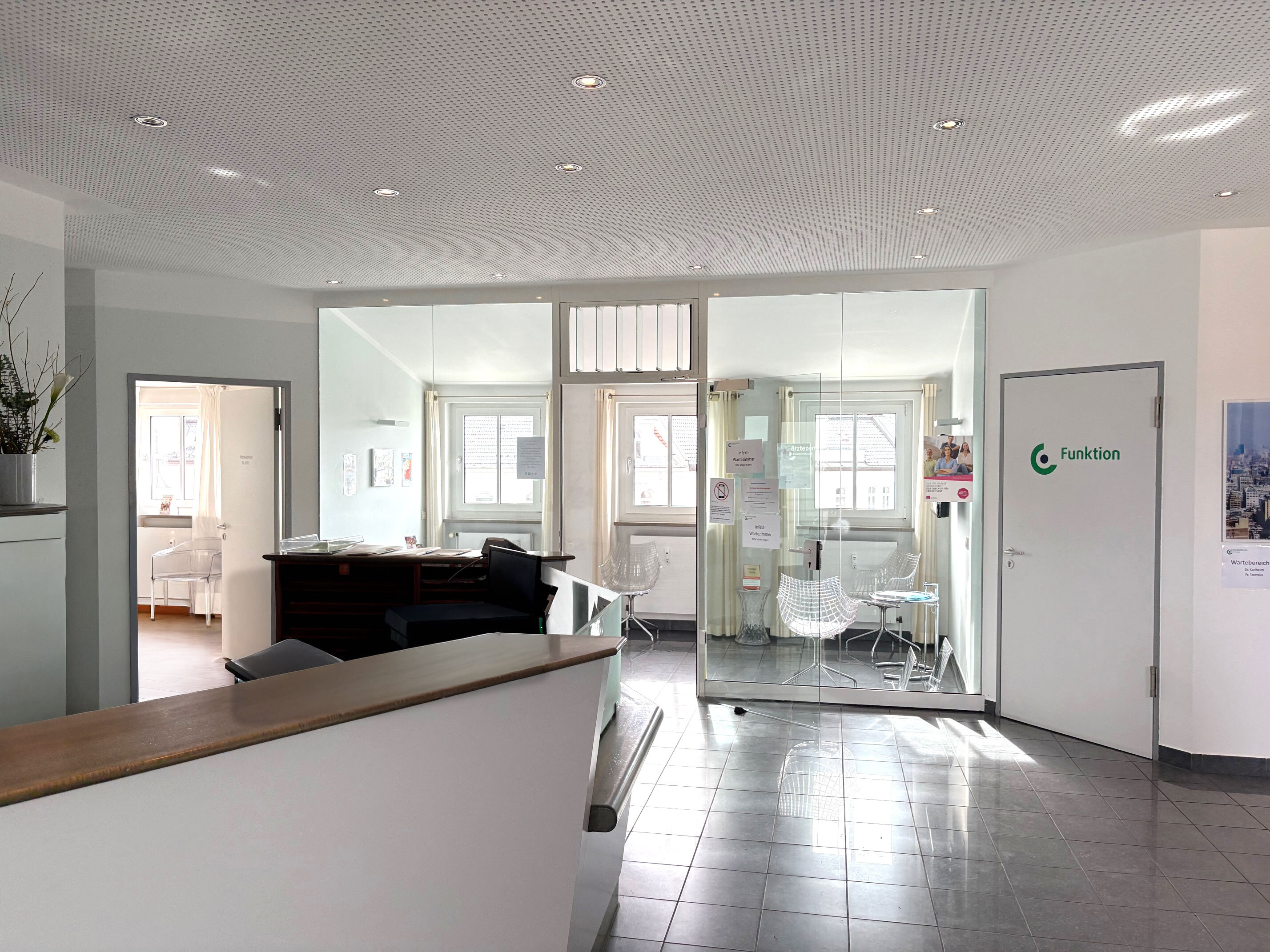 Heller Empfangsbereich des Ärztezentrum Einsteinstraße mit modernem Tresen und Glas-Wartezone in München.