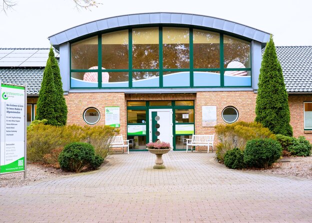 Eingangsbereich des Ärztezentrum Gorch Fock mit moderner Glasfront, rotem Backstein und gepflegtem Vorgarten.